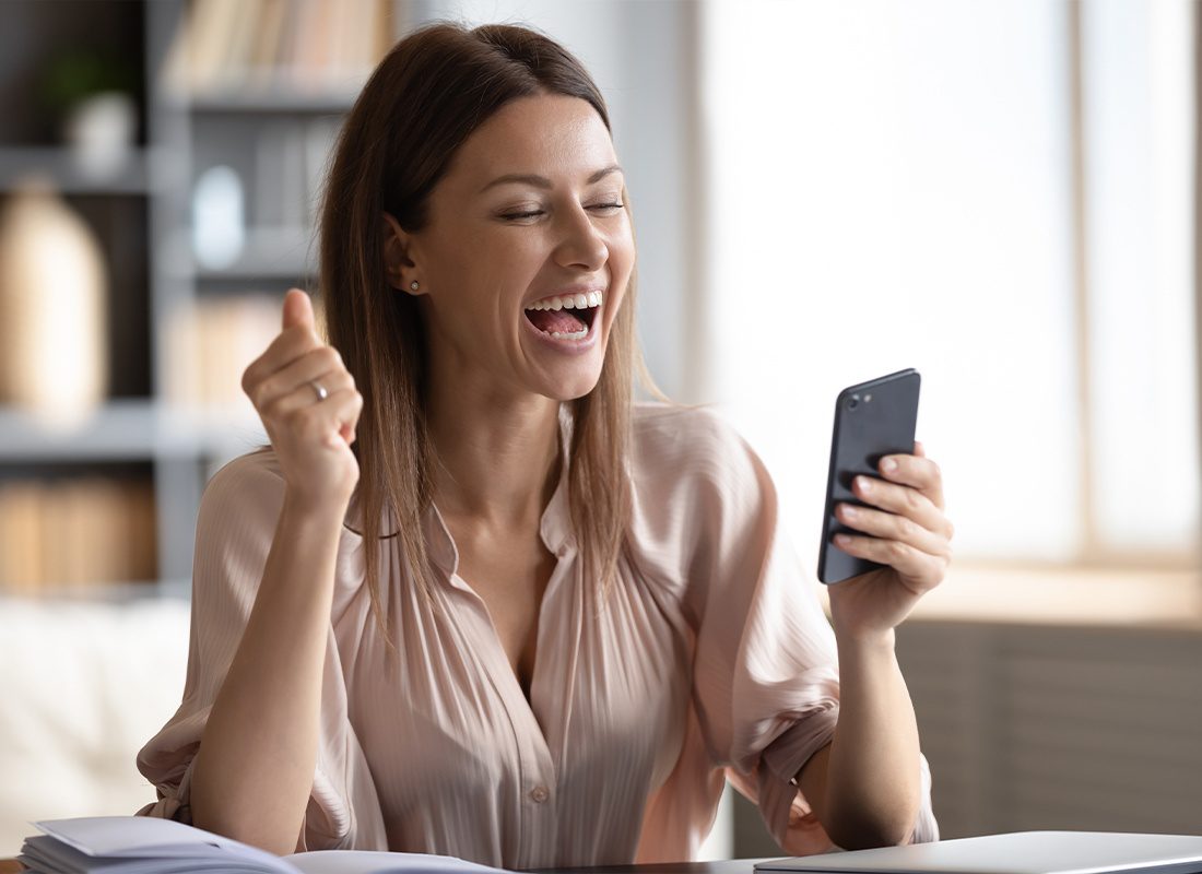 Review Us - Excited Woman Looking at Her Phone Screen and Reading Good News